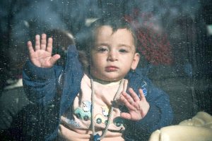 A migrant baby on the bus window on their way to the West, 2016.